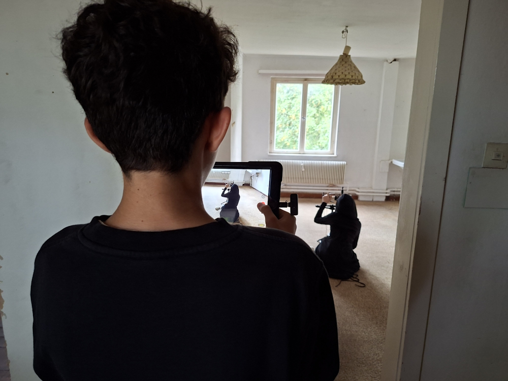 Eine Person filmt mit einem Tablet eine inszenierte Szene in einem Raum der Strahlenburg.