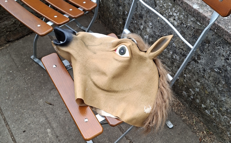 Pferdekopfmaske liegt zwischen Holzstühlen auf der Terrasse der Strahlenburg.