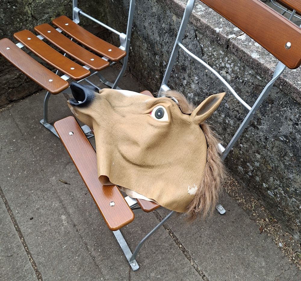 Pferdekopfmaske liegt zwischen Holzstühlen auf der Terrasse der Strahlenburg.